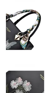 Detailed embroidery of flowers and butterflies with a silk scarf handle on a black handbag