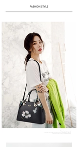 Detail of floral butterfly embroidery and colorful silk scarf wrap on a black tote bag