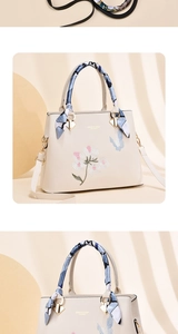 Detailed close-up of butterfly floral embroidery and silk scarf on cream handbag