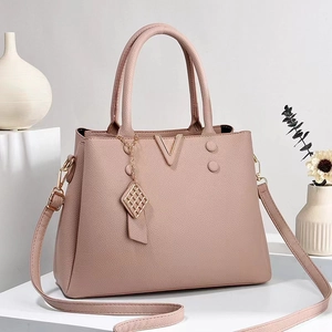 Sac à main chic rose poudré en cuir grainé avec détails dorés sur présentoir moderne