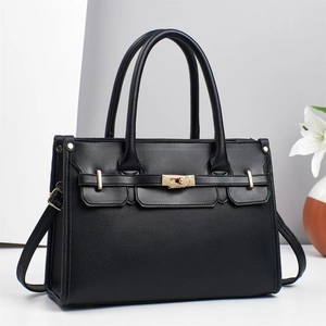 Close-up of black lychee grain tote bag with gold metal lock and leather strap detail