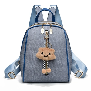 Blue denim backpack with leather trim and brown plush cloud charm in a clean front view