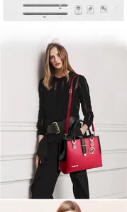 Detail van rood-zwarte handtas met gouden gespen en een hartvormige tashanger aan