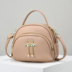 Pink lychee leather crossbody bag with gold flamingo logo and elegant pearl tassels