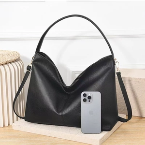 Detail of black pebbled leather tote bag with gold hardware and wide shoulder strap