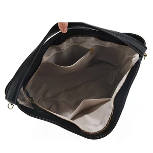 Close-up of black leather tote interior with zip pocket and herringbone fabric lining