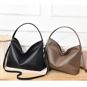 Detail of minimalist leather tote bags in black and dark brown with lychee pattern texture