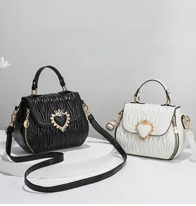 Detail of quilted crossbody bags with heart crown metal buckle in black and white