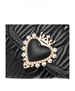 Close-up of quilted black leather bag with ornate golden heart crown buckle detail