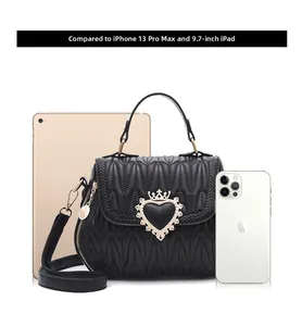 Quilted heart lock crossbody bag shown with iPad and iPhone for size comparison