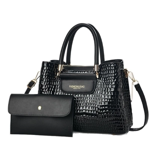 Black crocodile embossed tote bag and clutch set with gold hardware on white background