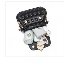 Top view of the interior capacity of a black quilted crossbody bag with daily essentials