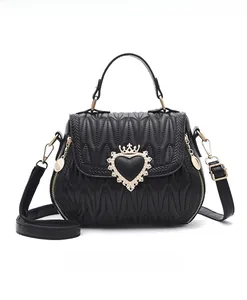 Detail of black quilted crossbody bag featuring a golden heart-shaped crown buckle