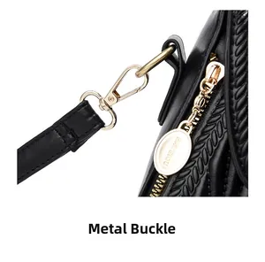 Close-up of golden lobster clasp and branded metal tag on a black quilted crossbody bag