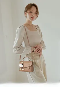 Close-up of brown pebbled leather crossbody bag with cute cat charm accessory