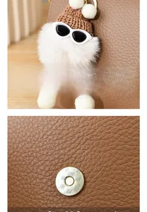 Detail of cute white plush charm on brown leather bag with metallic magnetic buckle