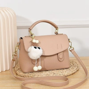 Detail of pink satchel featuring pebble texture with a plush cartoon charm on a woven mat