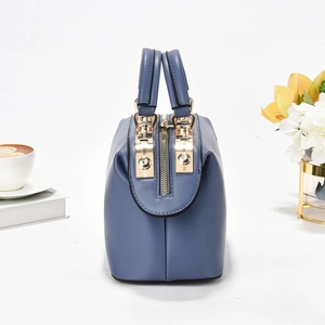 Detail of blue leather boston bag with golden hardware and flower decorations