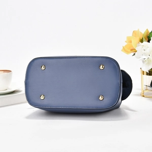 Detail of blue leather bag bottom with four protective golden metal feet and fine stitching