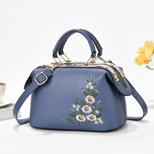 Navy blue vintage pillow bag with floral embroidery and gold hardware on white background