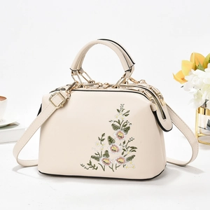 Elegant cream shoulder bag featuring floral embroidery and gold metal hardware accents