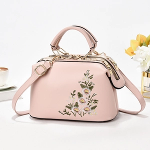 Elegant pale pink pillow handbag with floral embroidery and golden metal hardware
