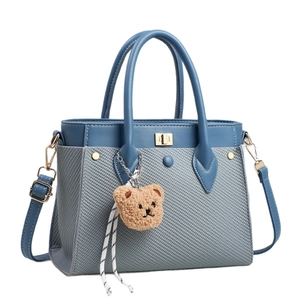 Borsa a mano blu in materiali misti con tracolla regolabile e ciondolo a orsetto
