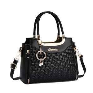 Chic black handbag with woven texture, golden metal handles and clover charm accessory