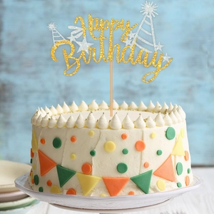 Glittering Happy Birthday cake topper with stars and party hat on a colorful cream cake