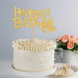 Glittering gold Happy Birthday cake topper with stars on a white cream cake