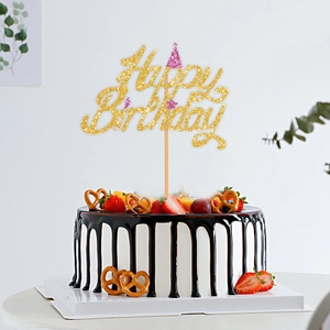 Golden glitter Happy Birthday cake topper with pink hat on a fresh cream fruit cake