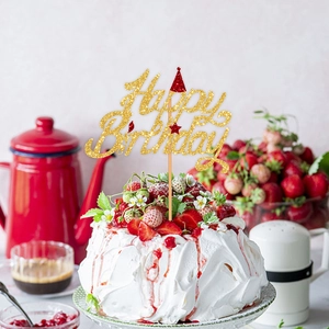 Close-up of golden glitter Happy Birthday cake topper on cream cake with fresh berries