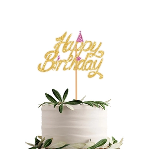 Close-up of golden Happy Birthday cake topper with pink glitter hat on a white cake