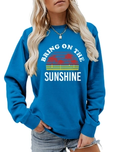 Detail of blue sweatshirt showing sunset palm tree graphic and white text embroidery