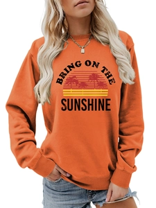 Detail of orange sweatshirt featuring Bring On The Sunshine graphic with sunset palm trees