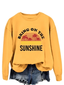 Detail of sunshine graphic print and palm tree design on a yellow crewneck sweatshirt