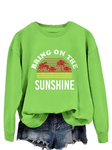 Close-up of Bring On The Sunshine slogan and sunset palm tree print on green sweatshirt