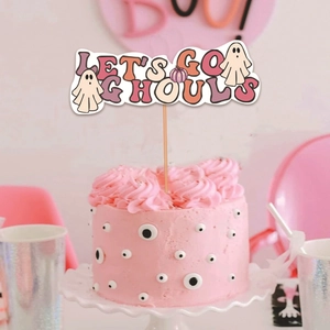 Let's Go Ghouls Halloween cake topper with pink ghosts and pumpkin on a festive dessert