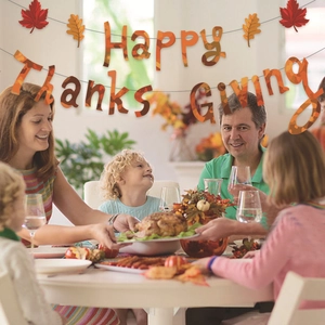 Happy Thanksgiving banner with maple leaf decorations in a warm family dinner setting