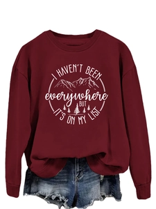 Close-up of travel slogan print on burgundy crewneck sweatshirt with mountain graphics