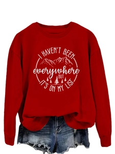 Detail of red crewneck sweatshirt featuring white mountain graphics and travel quote