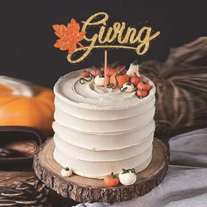 Glittering Giving Thanksgiving cake topper with orange maple leaf on a cream cake