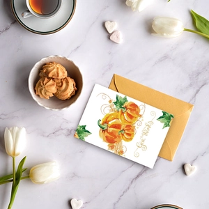 Flat lay of watercolor pumpkin Give Thanks card with envelope on marble background