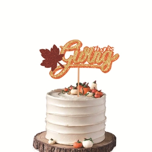 Glittery gold Thanksgiving cake topper with red maple leaf on a white cream cake