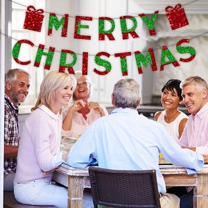 Red and green glitter Merry Christmas banner hanging in a warm festive dining room
