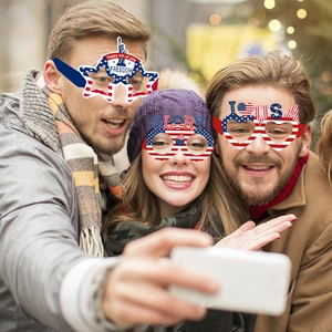Three people wearing red white and blue July 4th party glasses at an outdoor celebration