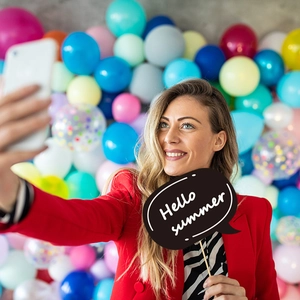 Donna in blazer rosso con accessorio Hello Summer a una festa hawaiana con palloncini