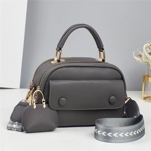 Detail of dark grey litchi grain leather crossbody bag with geometric woven strap