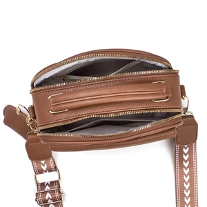 Detail view of brown pebbled leather crossbody bag with dual zippers and woven strap