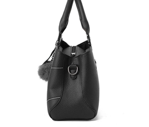 Detail of black pebbled leather texture on ladies handbag with white stitching and D-ring